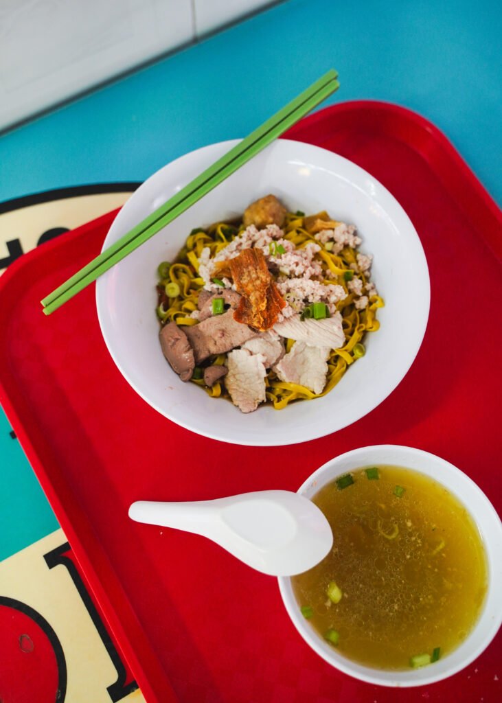 A bowl of noodles and soup on a red tray