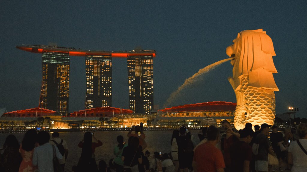 Merlion statue overlooking the bay in Singapore at night with Marina Bay Sands in the back