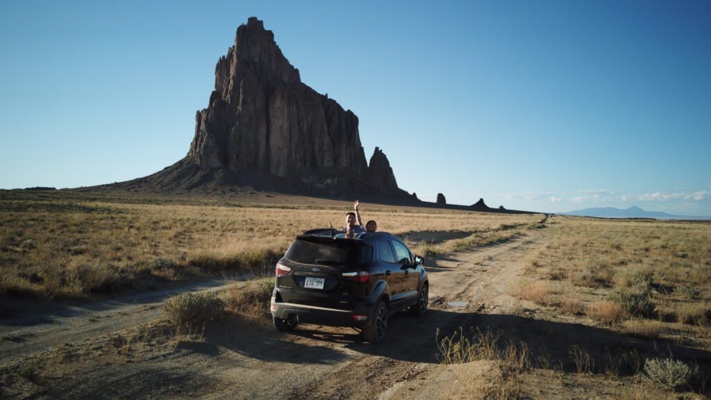 Couple in vehicle parked in front of shiprock monument, new mexico